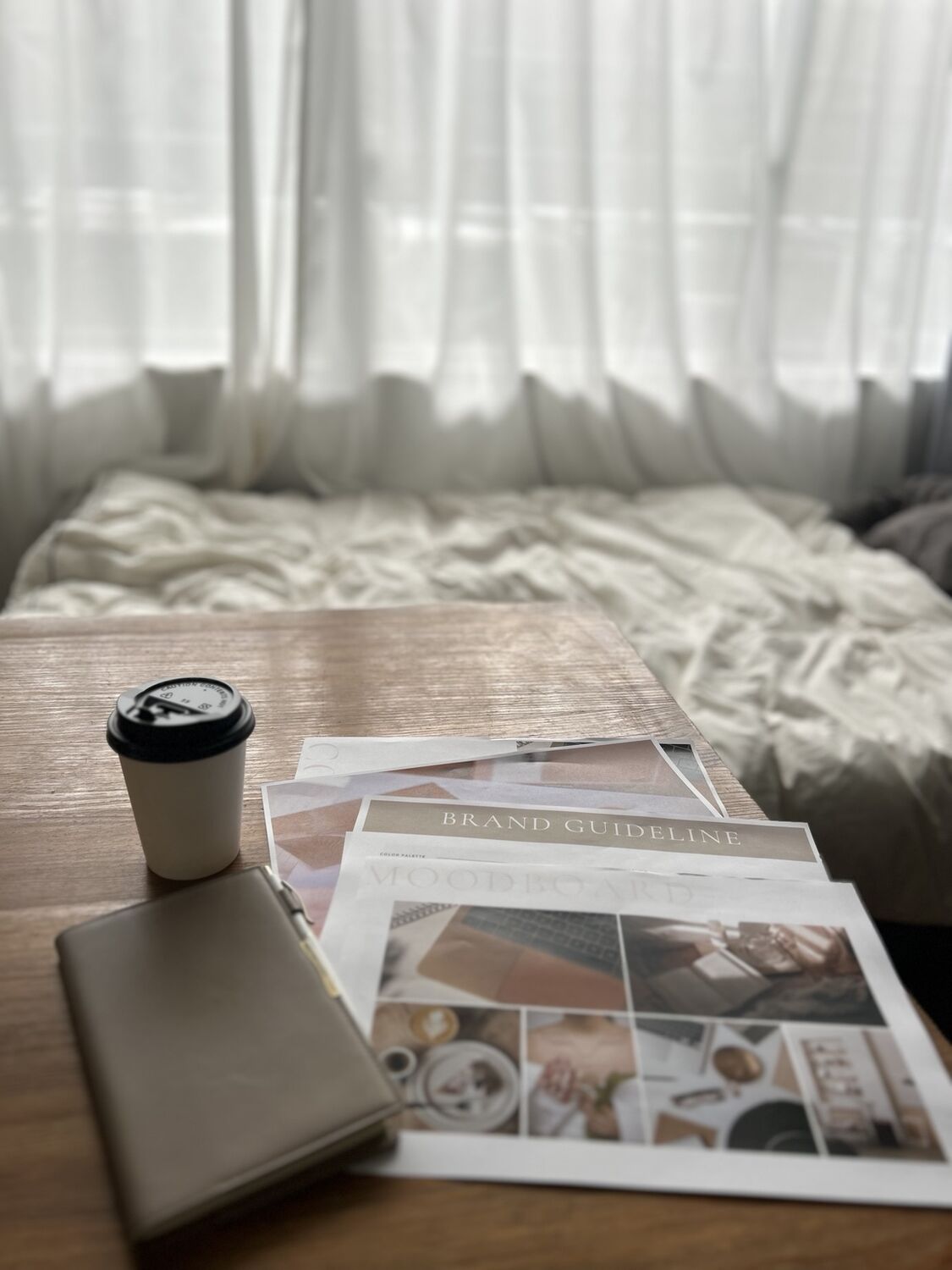 光の入る机に、手帳とブランド資料が置かれている様子